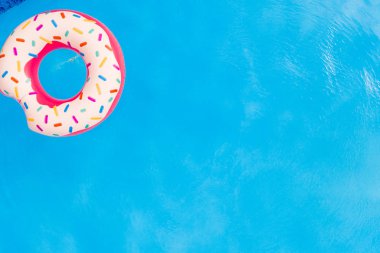 Yaz tatili. Yüzme havuzunda büyük pembe donut havadan görünümü.