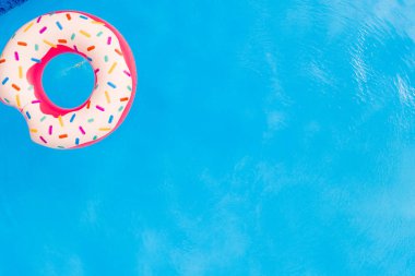 Summer Vacation. Aerial view of big pink donut in the swimming pool. clipart