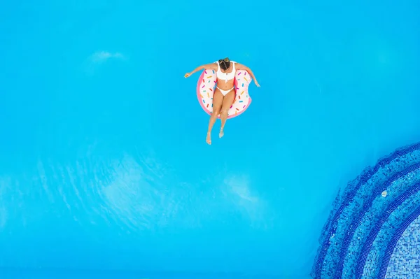 年轻的漂亮女孩在白色比基尼在游泳池的充气甜甜圈放松的鸟瞰图 — 图库照片