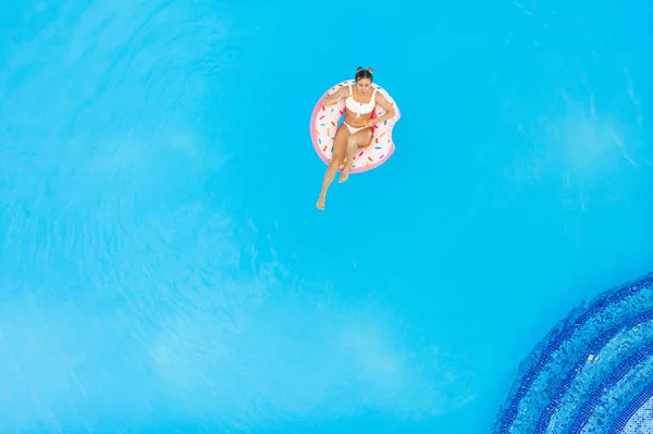 年轻的漂亮女孩在白色比基尼在游泳池的充气甜甜圈放松的鸟瞰图 — 图库照片