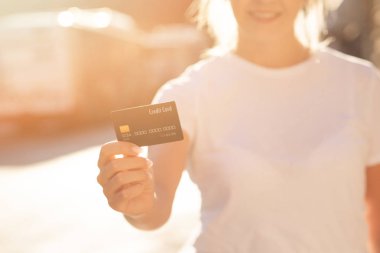 Kredi kartı tutan güzel gülümseyen sarışın kız. Kredi kartı olan bir kadının yakın çekim çekimi, Wolrd etrafında seyahat Online alışveriş