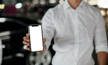 Otoparkta akıllı telefon kullanan bir adam. Park yerindeki akıllı telefonun boş ekranı