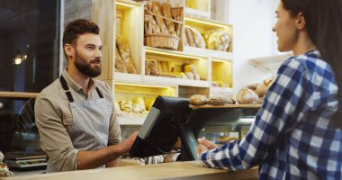 Ekmek dükkanında beyaz bir genç satıcı, ekmek almadan önce ekmek seçen genç ve güzel bir bayan alıcıyla konuşuyor..