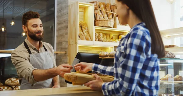 Hombre Guapo Vendedor Panadería Vendiendo Baguettes Joven Ella Pagando Con —  Fotos de Stock