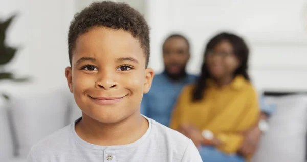 Portrait of african american little boy looking at camera on background of her parents. — Stock Photo, Image