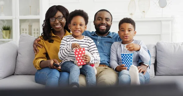 Gelukkig afrikaans amerikaans familie kijken tv eten popcorn snack plezier thuis. — Stockfoto