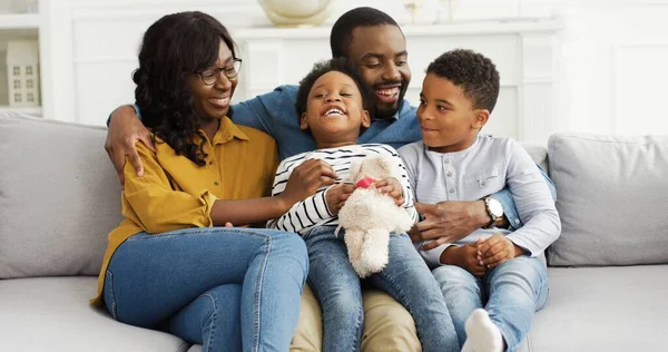 アフリカ系アメリカ人の両親の肖像で、小さな子供たちが家でソファに休んでいます. — ストック写真