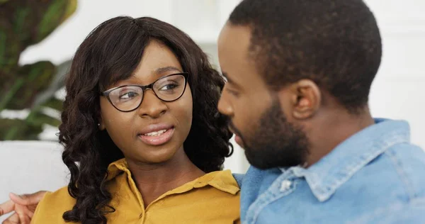 Feliz casal afro-americano marido e mulher sentados no sofá em casa . — Fotografia de Stock