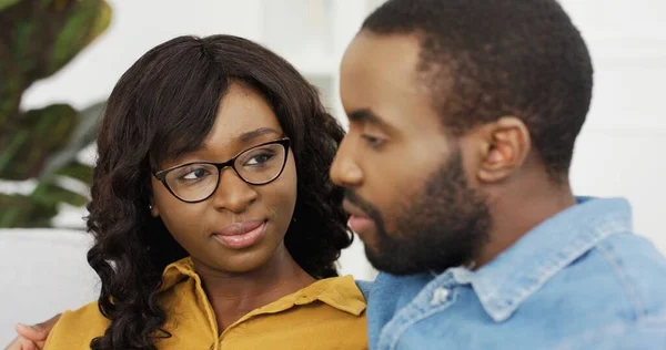 Feliz casal afro-americano marido e mulher sentados no sofá em casa . — Fotografia de Stock