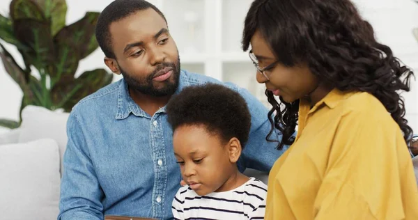 Happy Afro-Amerikaanse familie zitten op de bank met behulp van tablet thuis. — Stockfoto