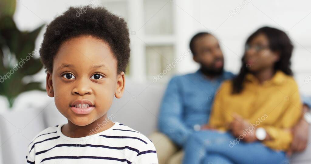 Portrait of african american little girl looking at camera on background of her parents.