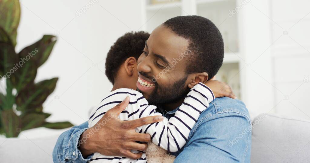 Portrait of African American dad hugging his cute little daughter. Happy Fathers day.