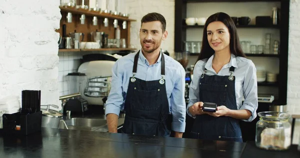 Bakre delen av den blonda kvinnan betalar med sin smartphone i baren samtidigt köpa en kaffe och servitör som serverar det. På caféet.. — Stockfoto