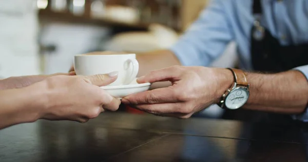 Közel a csésze kávét, amit a férfiak adnak a csapos kezéből a női ügyfélnek a kávézóban.. — Stock Fotó
