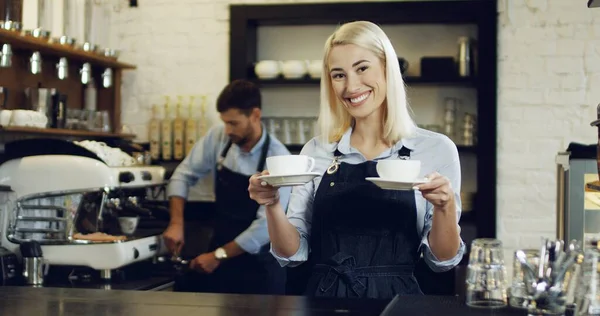 Männliche und weibliche Baristas arbeiten im Café. Frau hält Latte in den Händen — Stockfoto