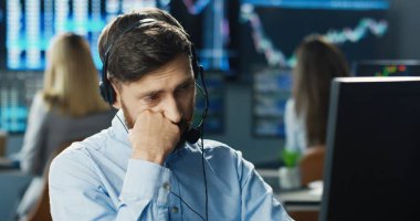 Borsa ofisinde çalışan borsacı ya da simsar portresi. İş ekibinin arka planındaki kulaklık ve bilgisayarı kullanıyor. Yatırım Girişimcisi Ticaret Konsepti.