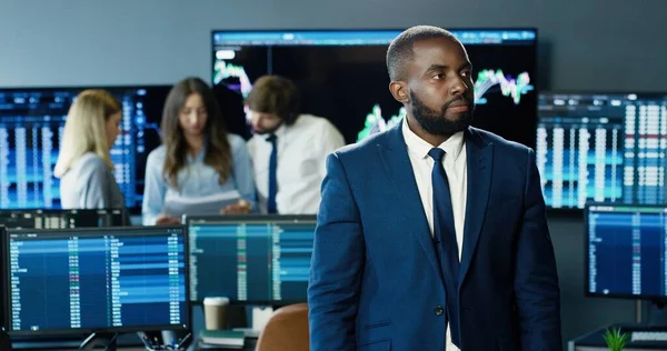 Portrait of african american trader or broker working at stock exchange office on background of his business team. Investment Entrepreneur Trading Concept