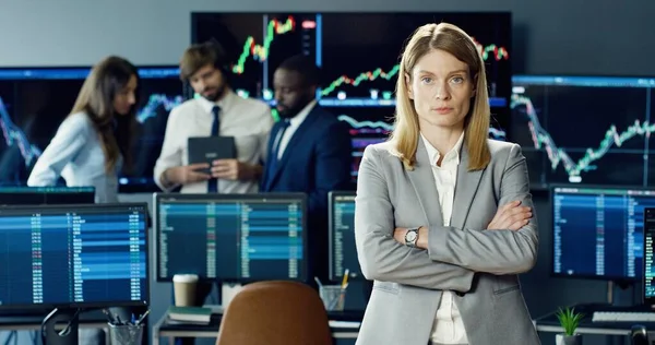 在证券交易所办事处工作的女性股票交易员或经纪人的画像 并在其业务团队的背景下看着镜头 — 图库照片