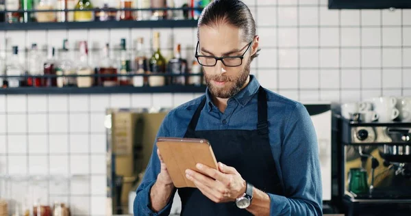 Bardaklı Önlüklü Beyaz Bir Erkek Mutfaktaki Kafede Tablet Kullanıyor Bar — Stok fotoğraf