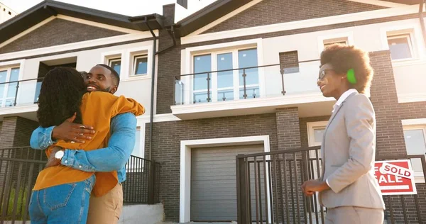 Kadın gayrimenkul, Afrikalı Amerikalı mutlu çifte ev satıp anahtarları veriyor. Dışarı çıkın. Neşeli evli erkek ve kadın kucaklaşıp, kenar mahalleden ev alıyorlar. Aşağıdan banliyö görünümünde konut alınıyor