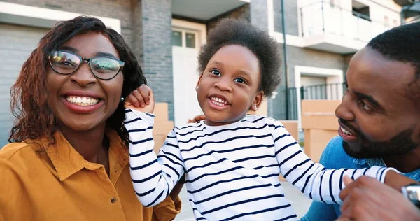 Africká americká mladá rodina s malou roztomilou dívkou usmívá a mluví s kamerou, zatímco videochatting venkovní. Usmála se šťastná matka, otec a dceruška chatují přes webkameru. Videochat. — Stock fotografie