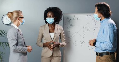 Karışık ırklar, kadınlar ve erkekler, arka planda fizik ya da matematik formülleriyle birlikte sınıfta çalışma kavramını tartışıyorlar. Çok ırklı erkek ve kadınlar ofiste iş büyümesinden bahsediyorlar.