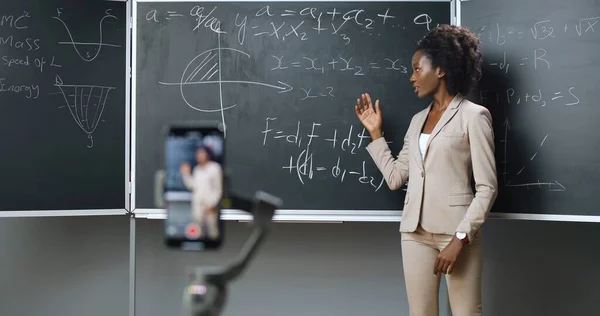 Smartphone opname video les op school. Online studeren. Afro-Amerikaanse jonge vrouwelijke leraar uitleggen wiskunde of natuurkunde formules in de klas. Quarantaine concept. Studeren via internet. Isolatie. — Stockfoto