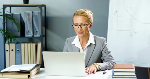 Кавказская деловая женщина в очках, сидящая в офисе и разговаривающая через веб-камеру на ноутбуке, видеочаты и обучающая бизнесу. Женщина тренер записи видео блог Blogger видеочат онлайн на компьютере. — стоковое фото