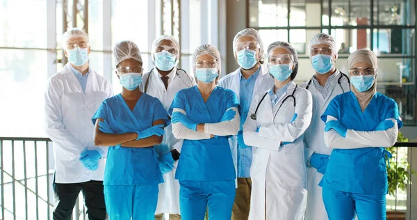 Team av blandade raser team av professionella män och kvinnor läkare på sjukhus. Inomhus. Internationell grupp av läkare i medicinska masker. Multietniska läkare i klänningar och uniformer på kliniken. — Stockfoto