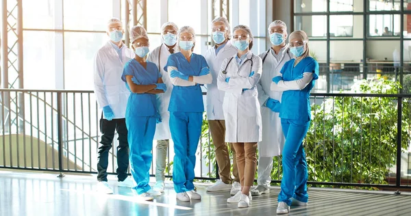 Team of mixed-races team of professional males and females doctors in hospital. Indoor. International group of medics in medical masks. Multi ethnic physicians in gowns and uniforms in clinic.