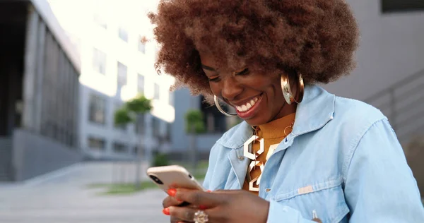 아프리카계 미국인아름다운 여성이 핸드폰으로 두드리고 스크롤하고 밖에서 있습니다 스마트폰에서 멋지고 — 스톡 사진