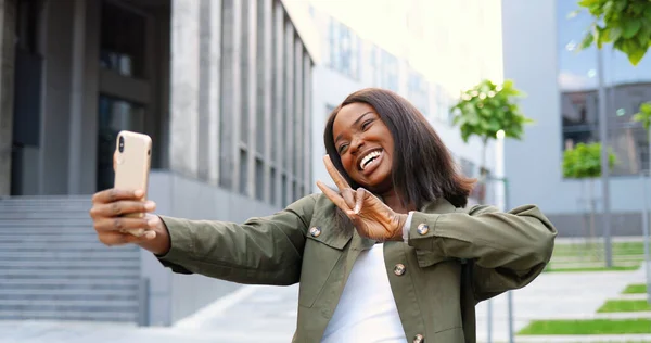 아름다운 아프리카 여성이 스마트폰 카메라에 포즈를 취하고 웃으면서 거리에서 사진을 — 스톡 사진
