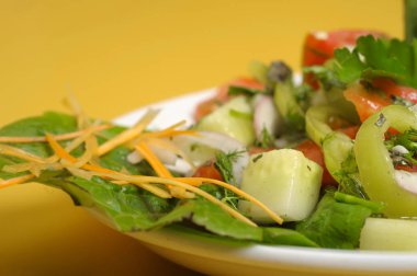 sarı bir tablo üzerinde beyaz bir tabak içinde taze yaz salatası