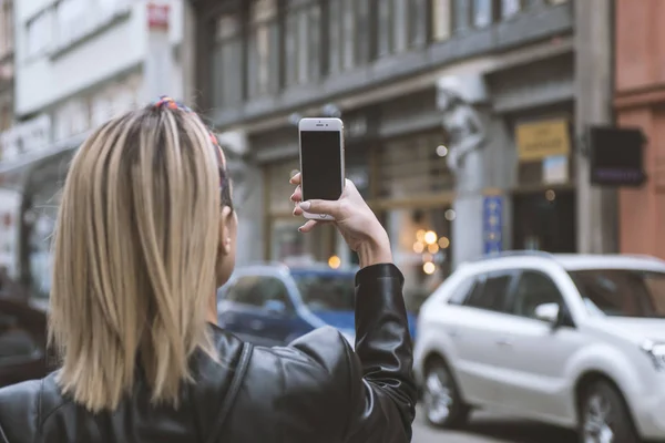 Woman tourist taking picture with mobile camera in the street