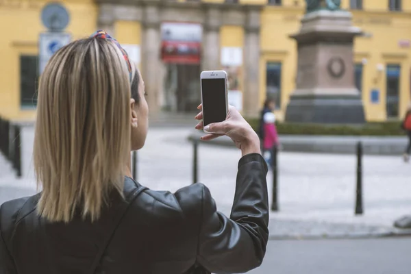 Woman tourist taking picture with mobile camera in the street