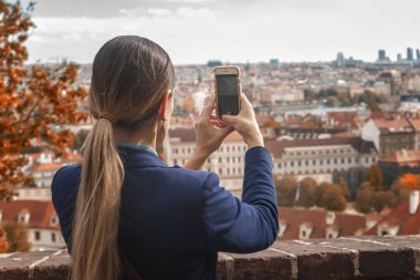 Kadın turist sokakta cep kamerasıyla fotoğraf çekiyor.