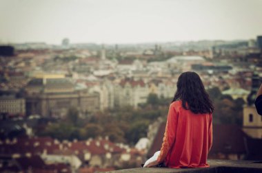 Arkadan bak. Bir sonbahar gününde şehrin manzarasının tadını çıkaran bir kadın.