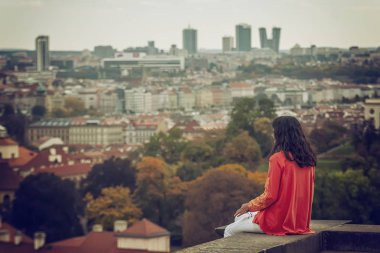 Arkadan bak. Bir sonbahar gününde şehrin manzarasının tadını çıkaran bir kadın.