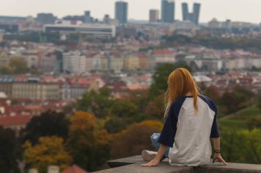 Arkadan bak. Bir sonbahar gününde şehrin manzarasının tadını çıkaran bir kadın.