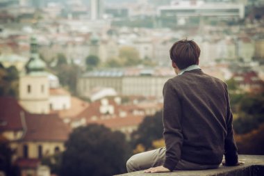 Arkadan görüntüleyin. Genç adam bir sonbahar gününde manzarayı şehir