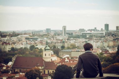 Arkadan görüntüleyin. Genç adam bir sonbahar gününde manzarayı şehir
