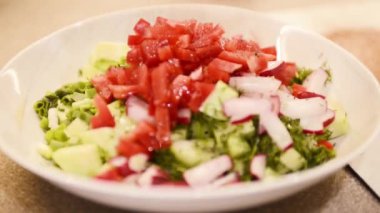The cook is preparing a salad. Pouring seasoning on vegetables