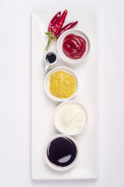 Mayonez, ketçap, hardal, soya sosu ve beyaz zemin üzerine biber