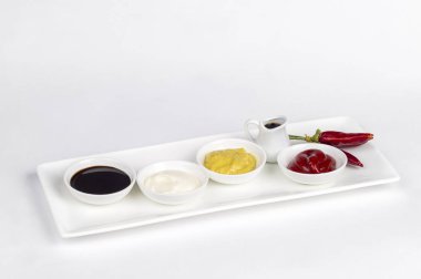 Mayonez, ketçap, hardal, soya sosu ve beyaz zemin üzerine biber