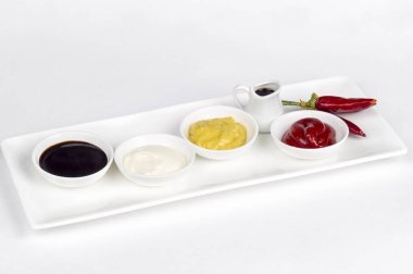 Mayonez, ketçap, hardal, soya sosu ve beyaz zemin üzerine biber