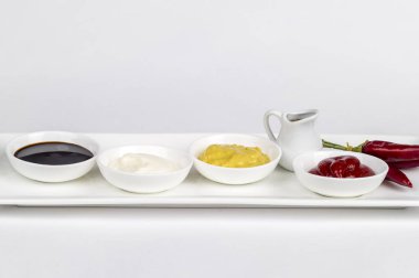 Mayonez, ketçap, hardal, soya sosu ve beyaz zemin üzerine biber