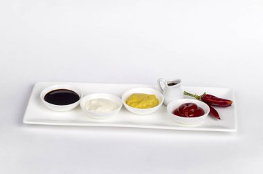 Mayonez, ketçap, hardal, soya sosu ve beyaz zemin üzerine biber