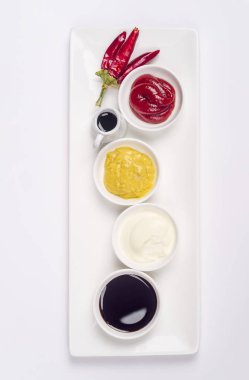 Mayonez, ketçap, hardal, soya sosu ve beyaz zemin üzerine biber