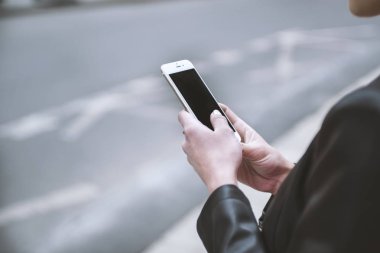 Kadın sokakta telefon tutarak. Cep telefonu ile yakın çekim kadının el