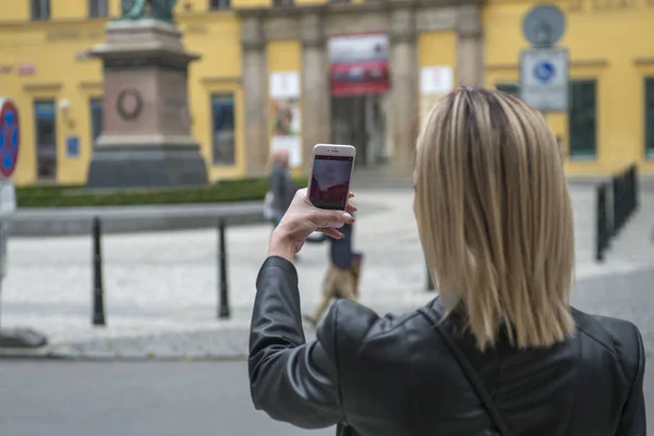 Woman tourist taking picture with mobile camera in the street